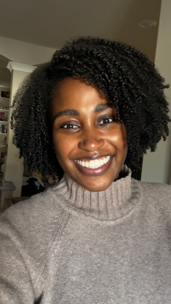 A smiling woman with defined, hydrated curls using The Doux 808 Gel and Chief Rocka Mousse for Defined Curls wash-and-go routine. Her hair looks soft, voluminous, and well-moisturized, highlighting the results of this curl-defining product combo.